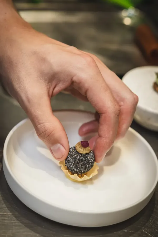 Een truffelbonbon wordt met de hand afgewerkt op een bladerdeeg tartelette
