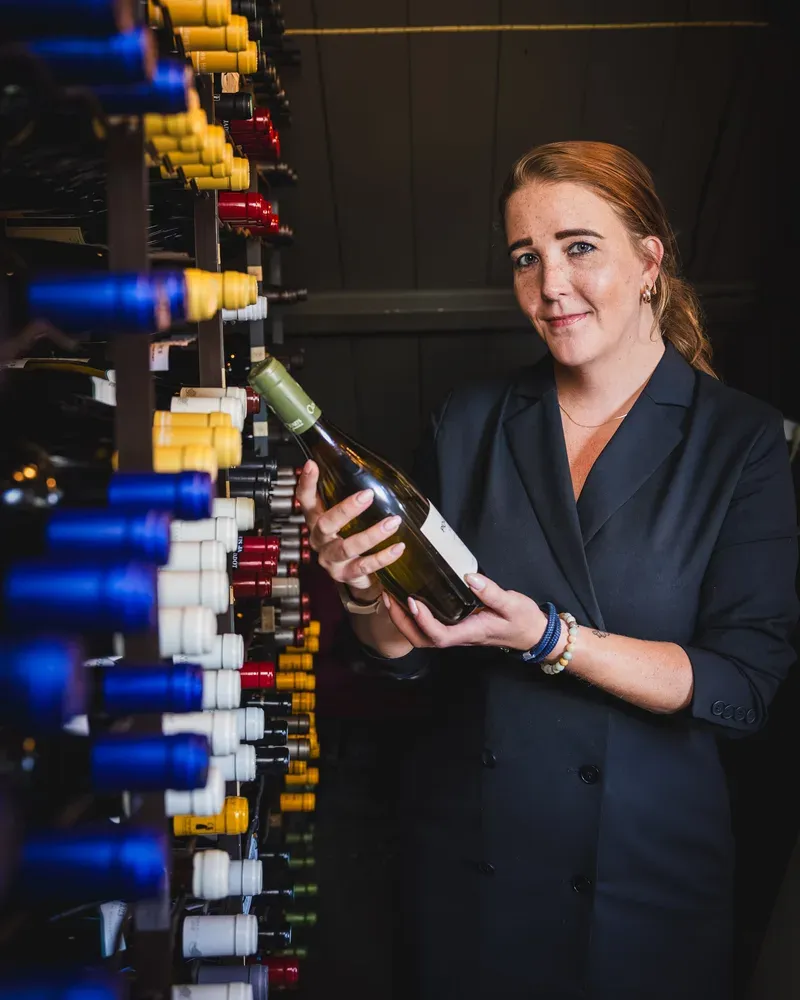 Our sommelier Livia van IJperen selecting a bottle from the Tante Koosje wine cellar