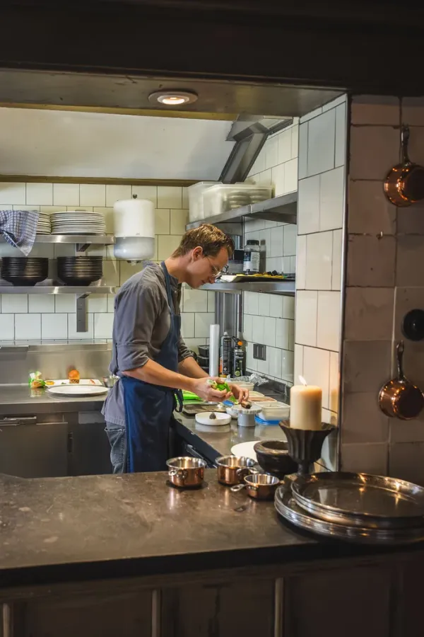 Junior sous-chef Paul van Randwijk werkt een bord af in de open keuken