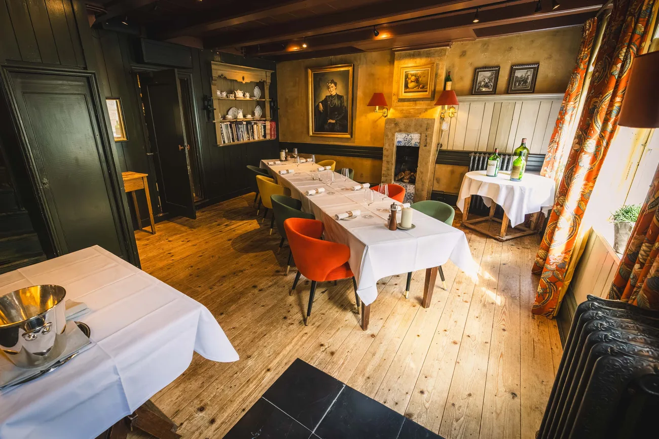 The Huiskamer at Tante Koosje: a long table set for a group, with the portrait of Koosje Edema on the wall