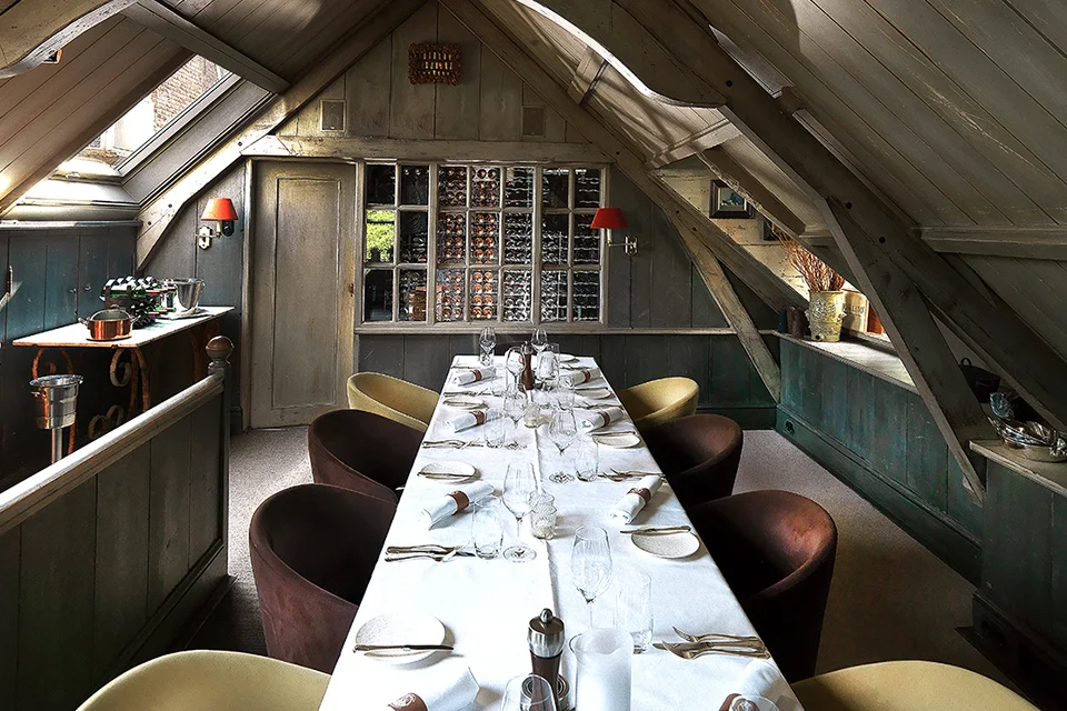 The Wine Loft at Tante Koosje: a table set for private dining under the roof beams, overlooking the wine collection